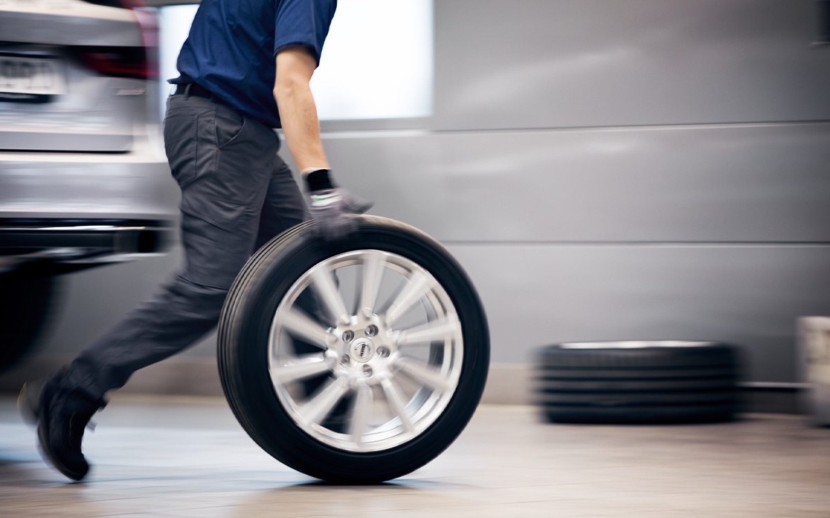 Garage employee rolls winter tyres through garage