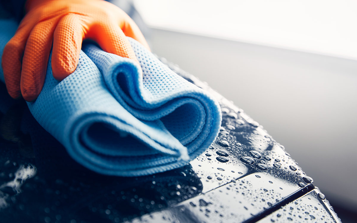 Person washes a car with a microfibre cloth