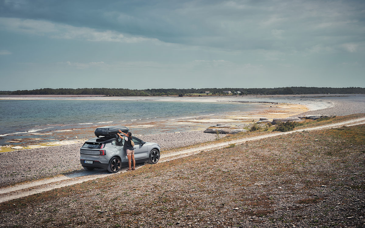 Person loads a rented roof box on a Volvo on the beach