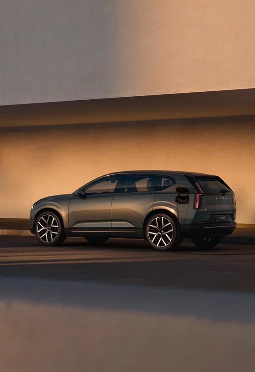 Volvo EX60 electric SUV driving on a road bathed in atmospheric evening lighting