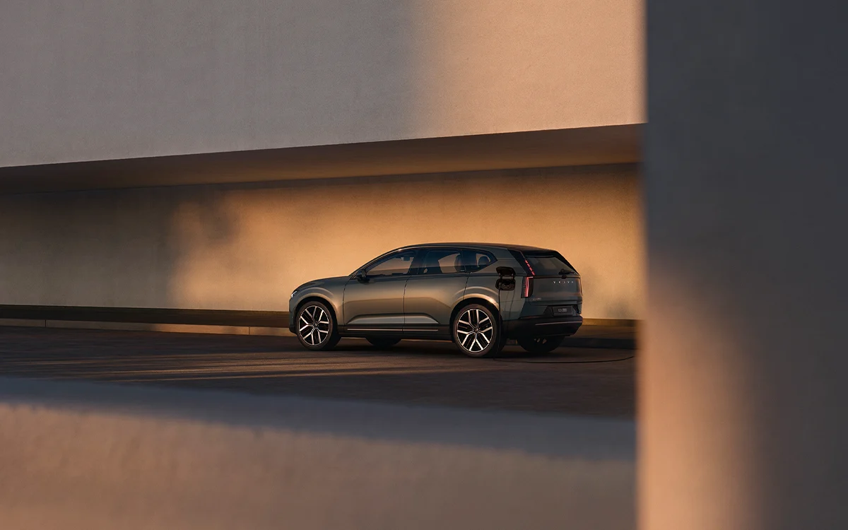 Volvo EX60 electric SUV driving on a road bathed in atmospheric evening lighting