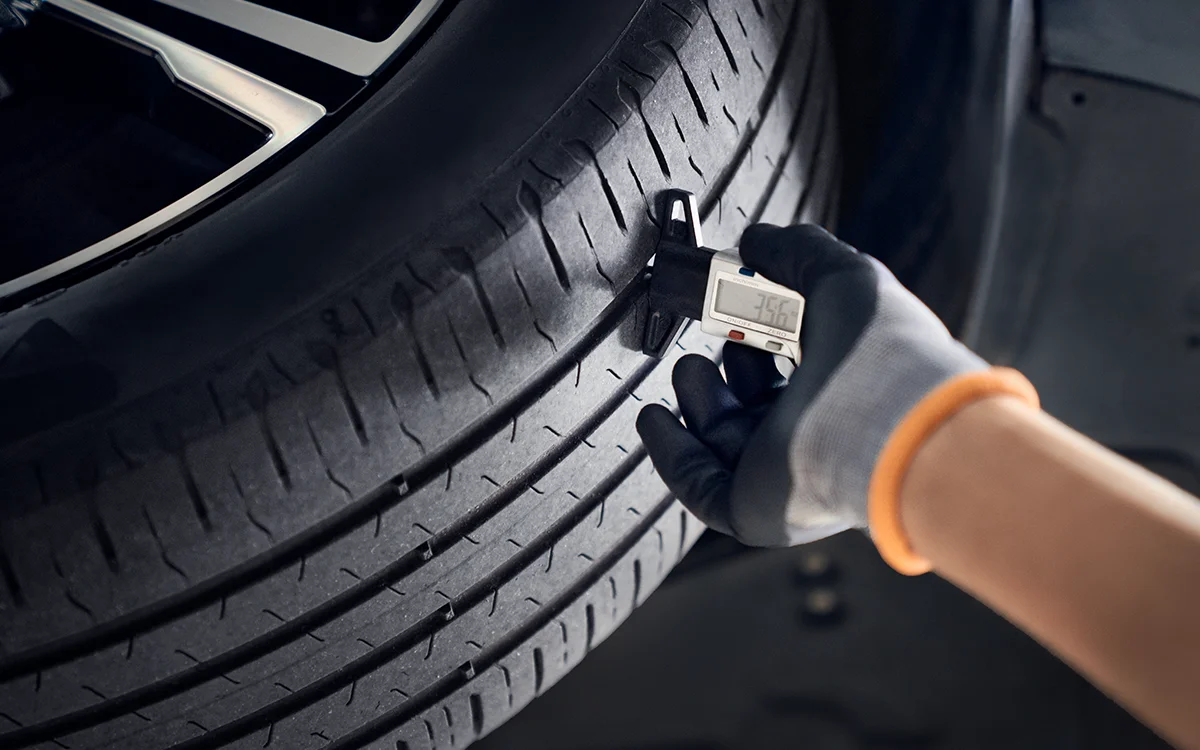 Changing tyres: Mechanic measures the tread depth of a car tyre