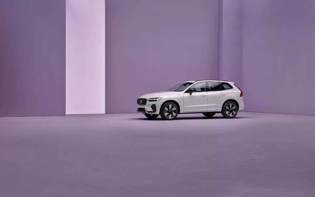 White Volvo XC60, front-side view, parked in front of a purple background