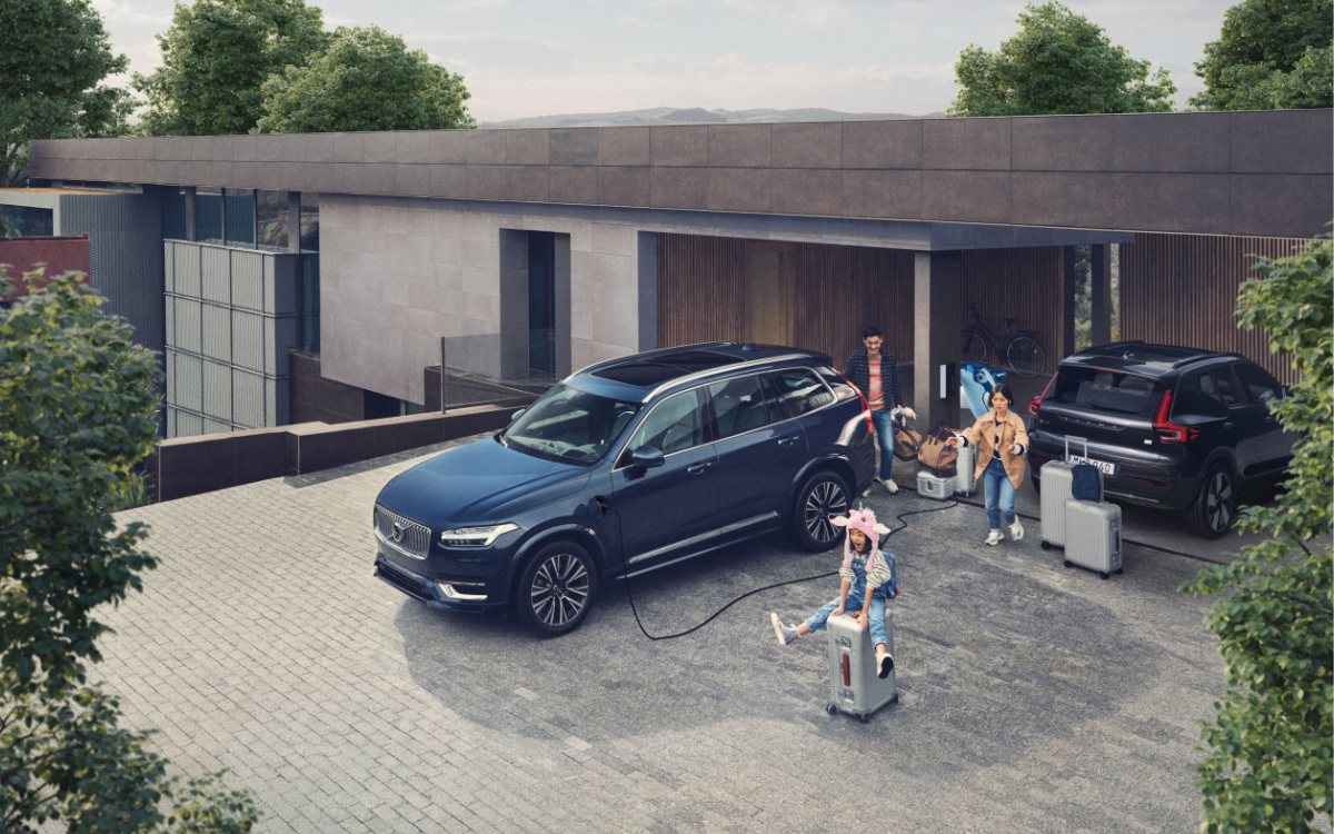 Volvo XC90 als Familienauto: Familie belädt den SUV vor dem Haus, Plug-in Hybrid am Ladekabel